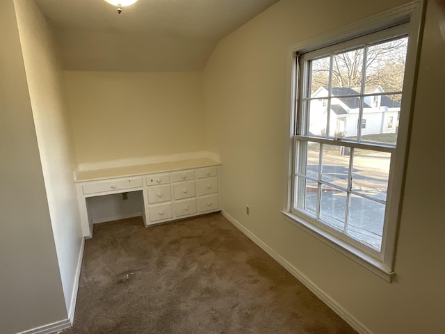 unfurnished bedroom featuring lofted ceiling, built in desk, and carpet