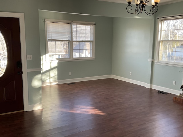 foyer with an inviting chandelier, ornamental molding, and dark wood-type flooring