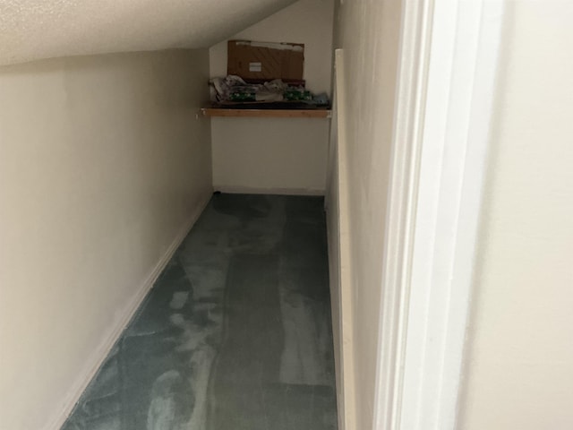 hallway with carpet flooring, vaulted ceiling, and a textured ceiling