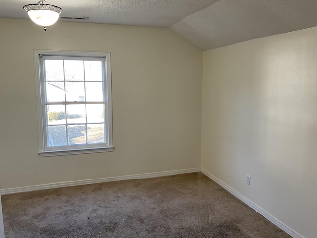 spare room with vaulted ceiling, carpet flooring, and a textured ceiling