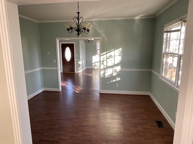 foyer entrance featuring dark hardwood / wood-style flooring, ornamental molding, and an inviting chandelier