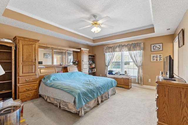 bedroom featuring light carpet, a textured ceiling, a raised ceiling, and ceiling fan