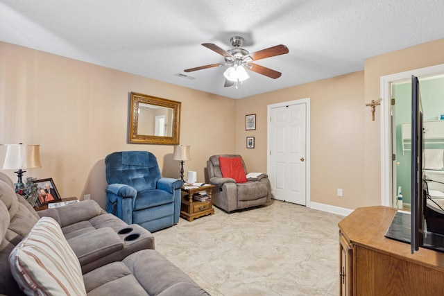 living room featuring ceiling fan and a textured ceiling