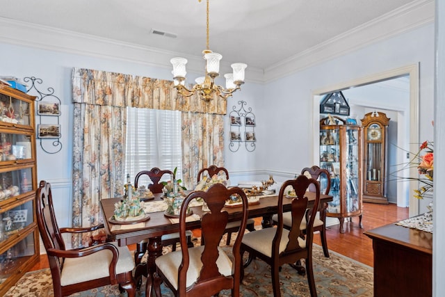 dining space featuring hardwood / wood-style floors, crown molding, and a notable chandelier