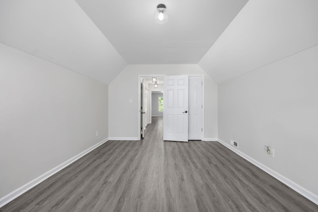 additional living space with dark wood-type flooring and lofted ceiling