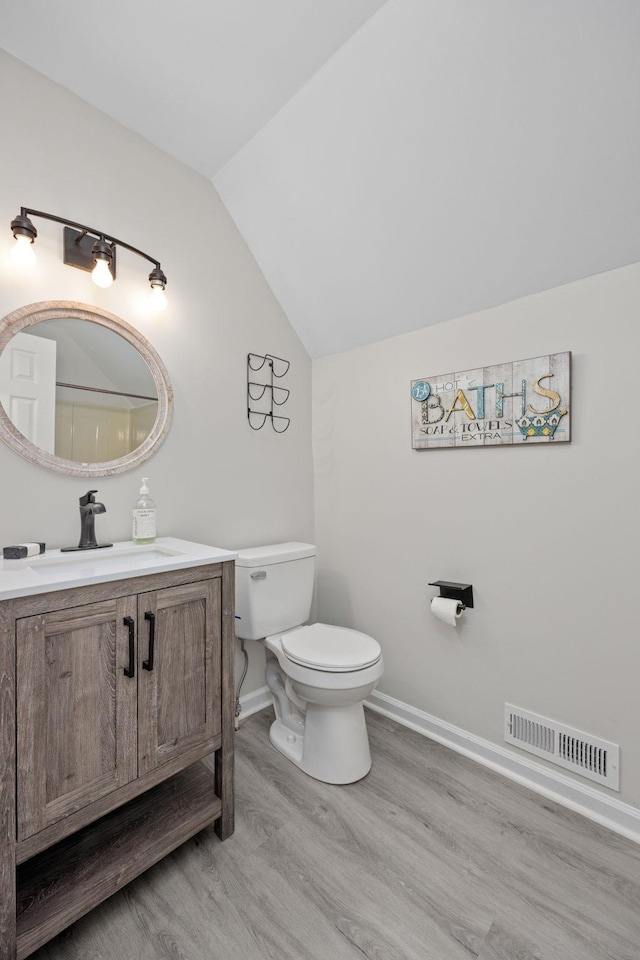 bathroom featuring hardwood / wood-style floors, vanity, toilet, and lofted ceiling