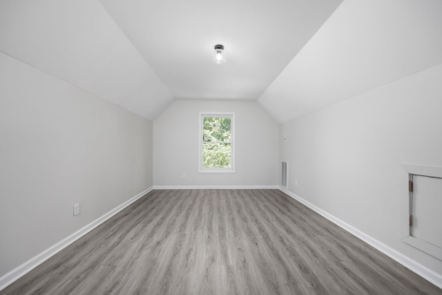 additional living space featuring light hardwood / wood-style floors and vaulted ceiling