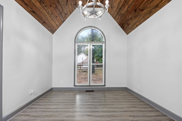 empty room with hardwood / wood-style floors, an inviting chandelier, vaulted ceiling, and wood ceiling