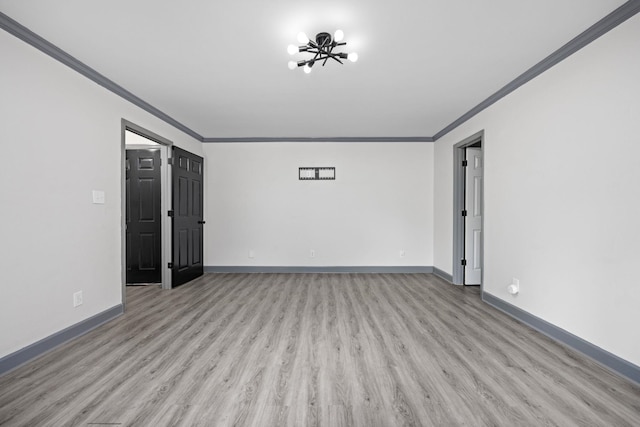 empty room featuring light hardwood / wood-style flooring, a notable chandelier, and ornamental molding