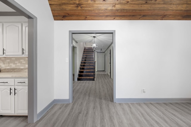 corridor with light hardwood / wood-style flooring, wooden ceiling, and lofted ceiling