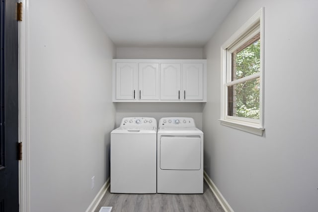 washroom with cabinets, separate washer and dryer, and light wood-type flooring