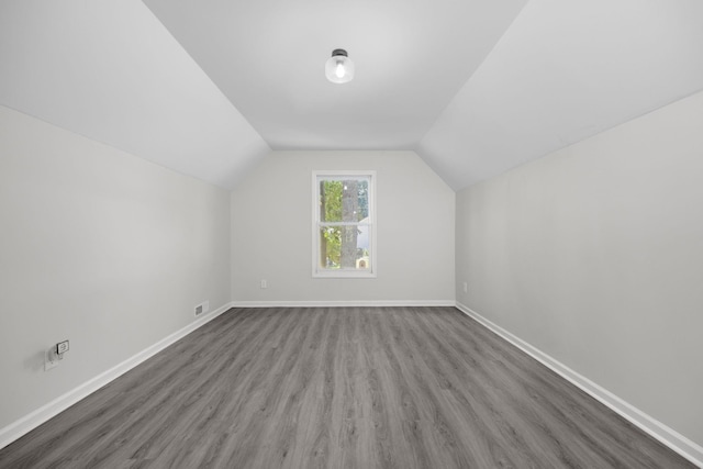 additional living space with wood-type flooring and vaulted ceiling