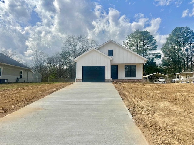 modern farmhouse with a garage, brick siding, concrete driveway, and fence