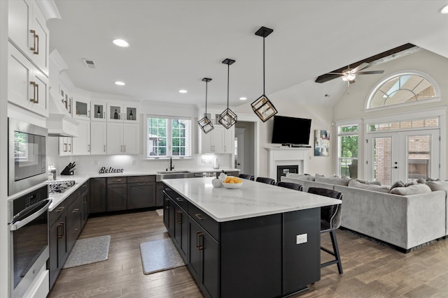  - kitchen with a sink, a kitchen island, white cabinetry, a ceiling fan, and appliances with stainless steel finishes