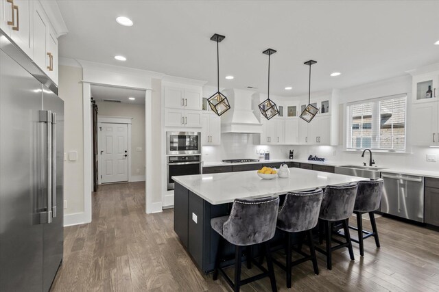  - kitchen featuring custom exhaust hood, a center island, light countertops, a sink, and stainless steel appliances