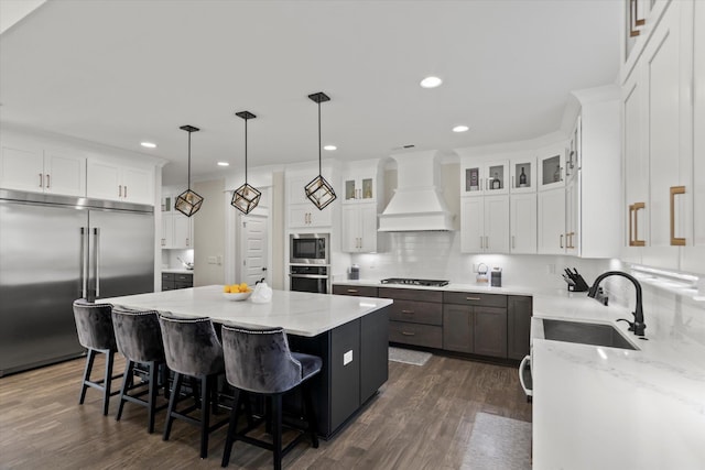  - kitchen with a center island, tasteful backsplash, premium range hood, dark wood-style floors, and built in appliances