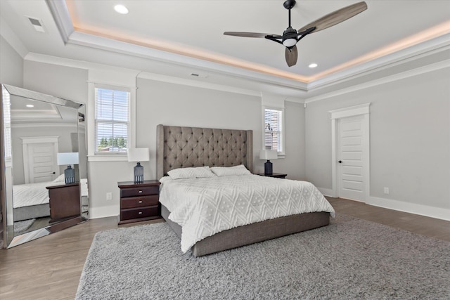  - bedroom with crown molding, a raised ceiling, and wood finished floors