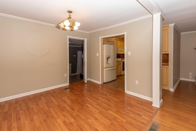 empty room with light wood-type flooring, ornamental molding, and a chandelier