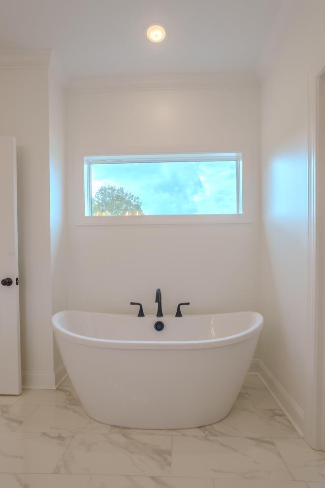 bathroom featuring a wealth of natural light, a bath, and ornamental molding