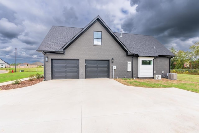 view of front property featuring cooling unit, a garage, and a front yard