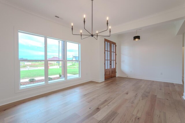 unfurnished dining area featuring a chandelier, french doors, light wood-type flooring, and ornamental molding