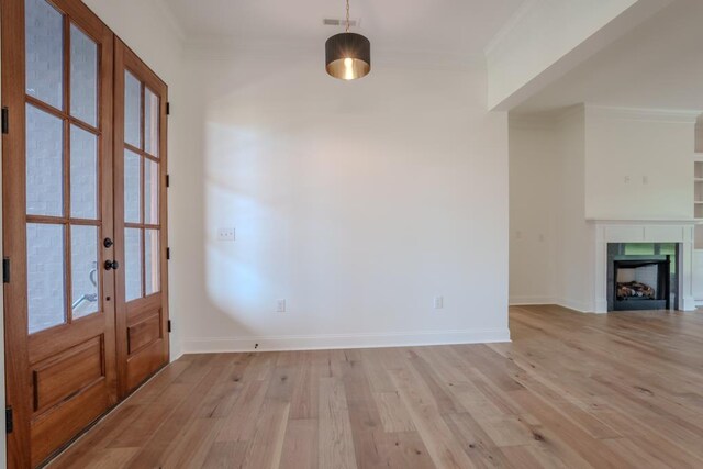 foyer entrance with light wood-type flooring, crown molding, and french doors