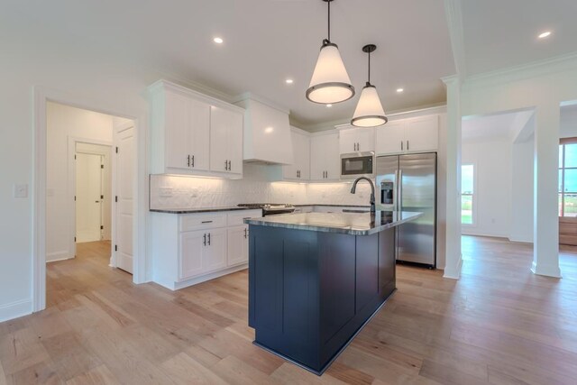 kitchen with white cabinets, sink, decorative light fixtures, light hardwood / wood-style floors, and stainless steel appliances