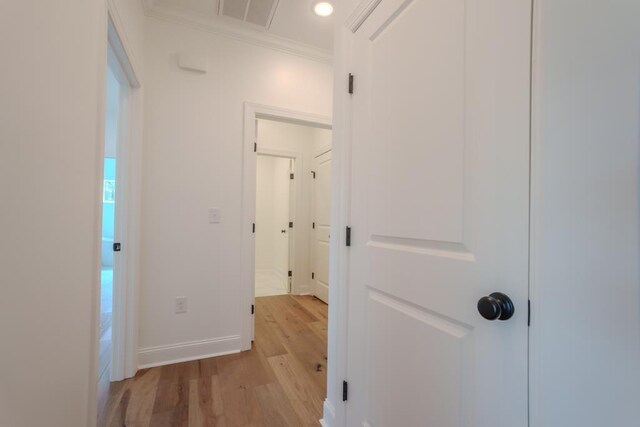 hallway featuring crown molding and light hardwood / wood-style flooring