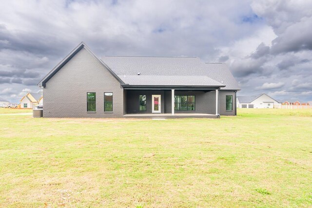 rear view of property with a lawn, central air condition unit, and a patio