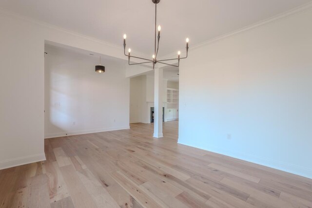 unfurnished dining area featuring a chandelier, crown molding, and light hardwood / wood-style floors