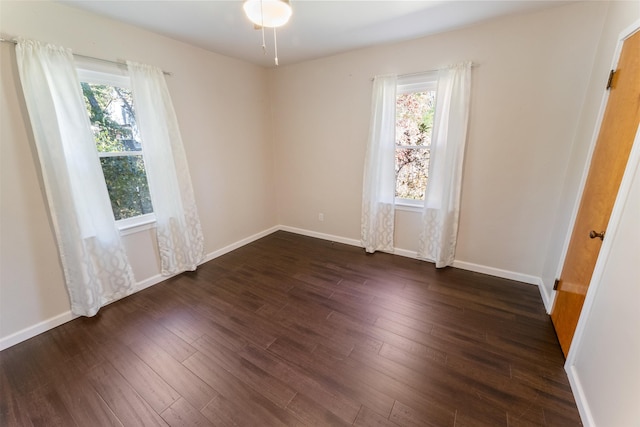 spare room with dark wood-type flooring and a healthy amount of sunlight