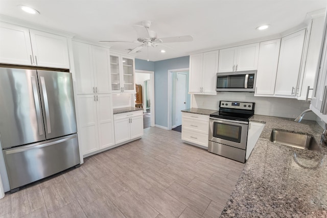 kitchen with white cabinets, stainless steel appliances, stone counters, and sink