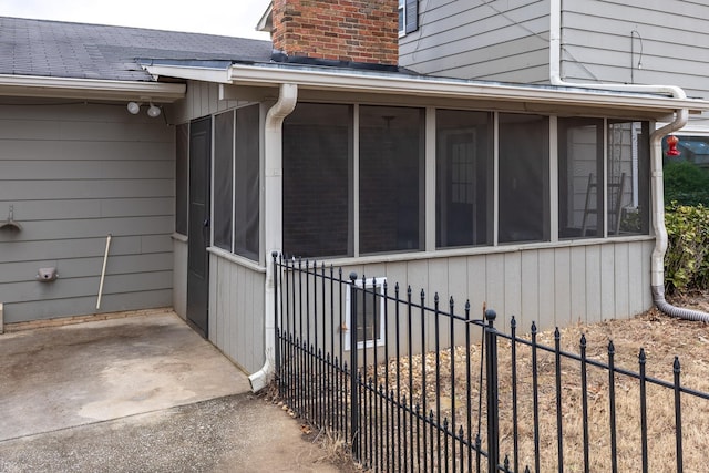 property entrance with a shingled roof, fence, and a chimney