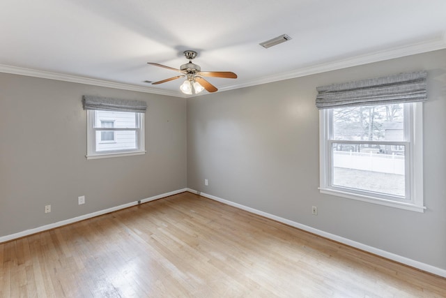 empty room featuring light wood-type flooring, visible vents, baseboards, and ornamental molding