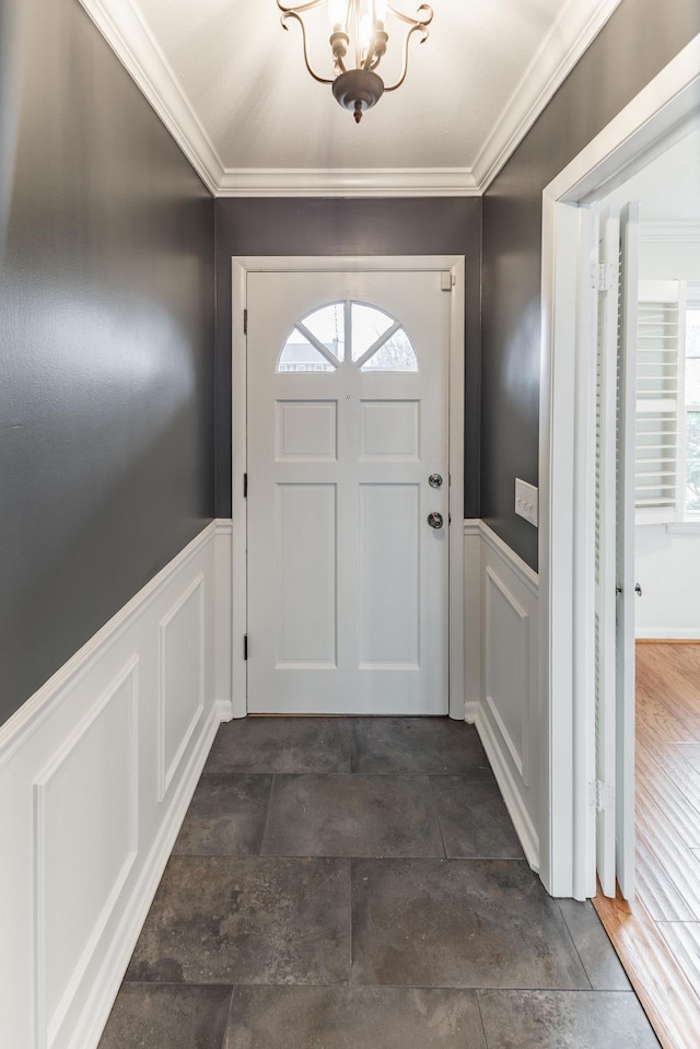 doorway with a wainscoted wall, a decorative wall, and crown molding