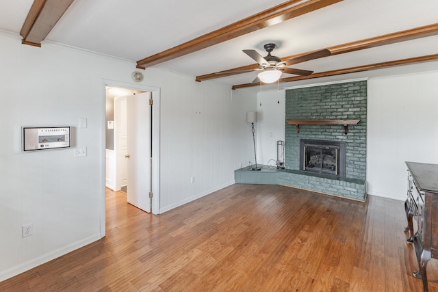 unfurnished living room featuring beamed ceiling, a fireplace, a ceiling fan, and light wood-style floors