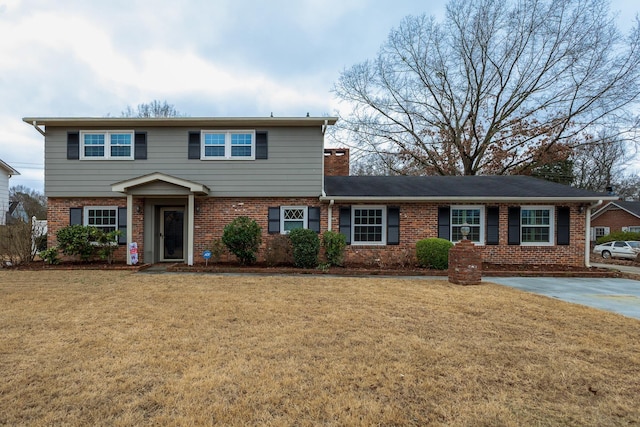 colonial-style house featuring a front yard, a chimney, and brick siding