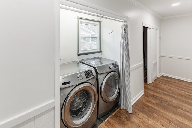 laundry area featuring a wainscoted wall, laundry area, dark wood-style flooring, ornamental molding, and washer and clothes dryer