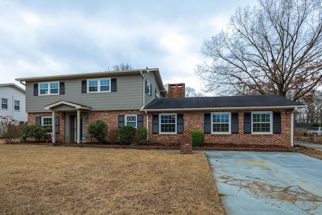 view of front of house featuring a front yard, brick siding, and a chimney