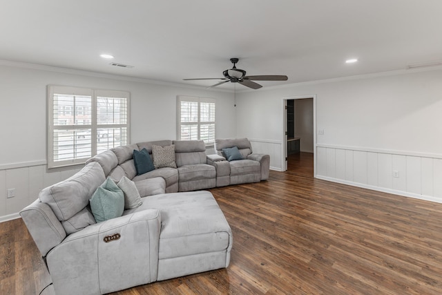 living room with a wainscoted wall, dark wood finished floors, visible vents, and crown molding