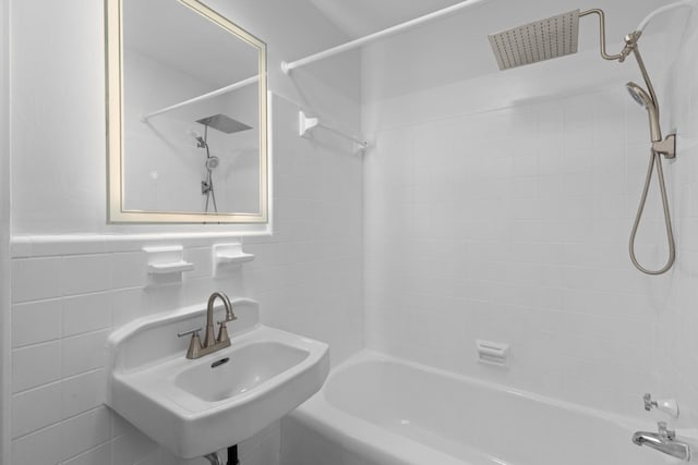 bathroom featuring tiled shower / bath, sink, and tile walls