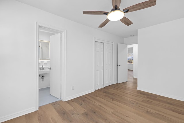 unfurnished bedroom featuring light hardwood / wood-style flooring, a closet, ceiling fan, and ensuite bathroom