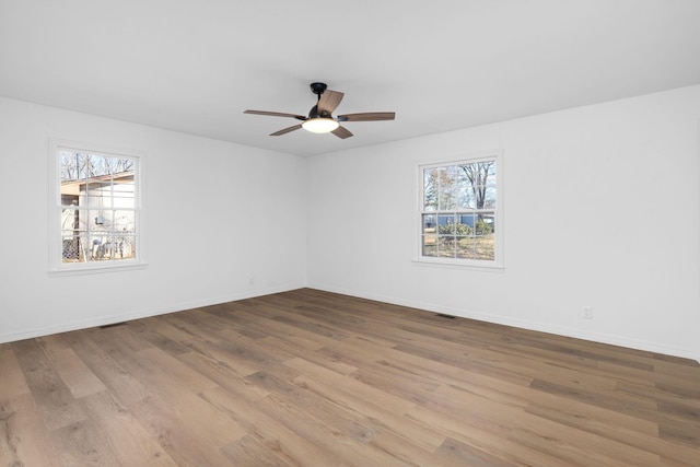 spare room with a healthy amount of sunlight, ceiling fan, and light hardwood / wood-style flooring