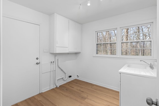 washroom with sink, cabinets, and light wood-type flooring