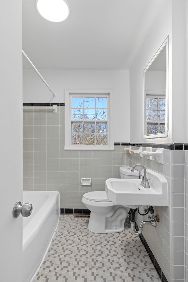 full bathroom featuring sink, tile walls, shower / bath combination, toilet, and tile patterned floors