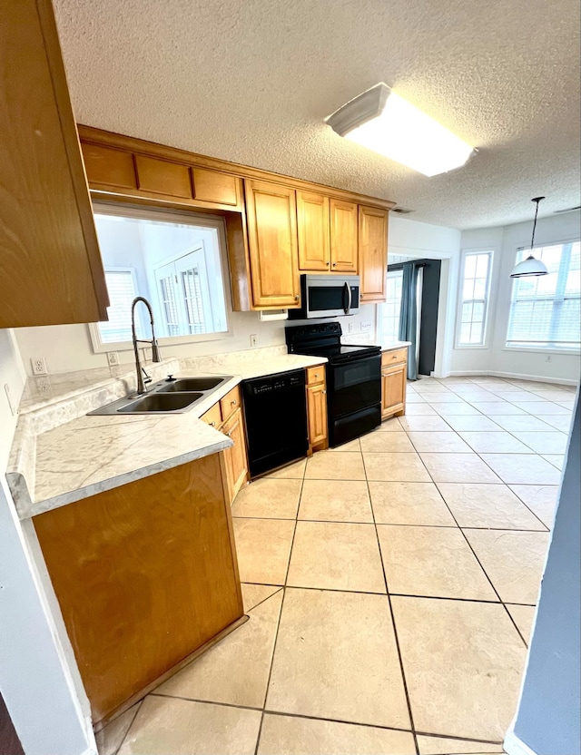 kitchen featuring sink, light tile patterned floors, hanging light fixtures, black appliances, and a textured ceiling