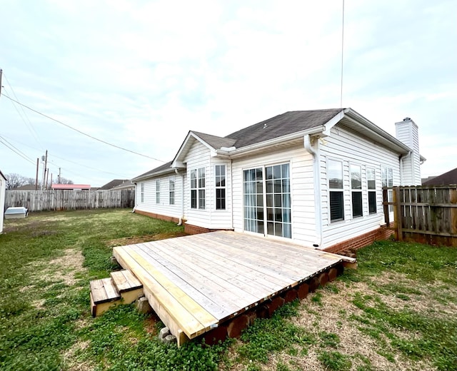 back of property featuring a wooden deck and a lawn