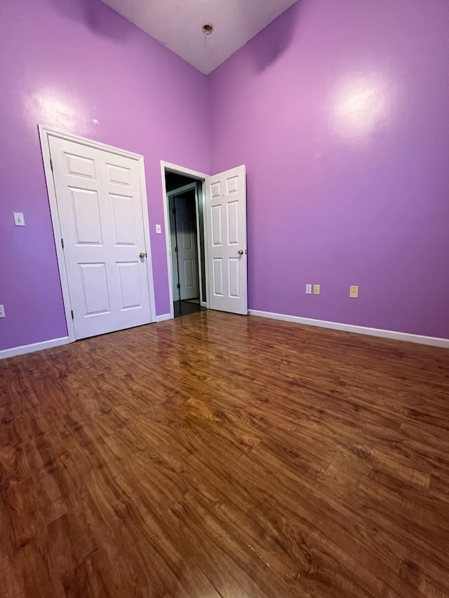 unfurnished bedroom featuring dark hardwood / wood-style flooring and a high ceiling