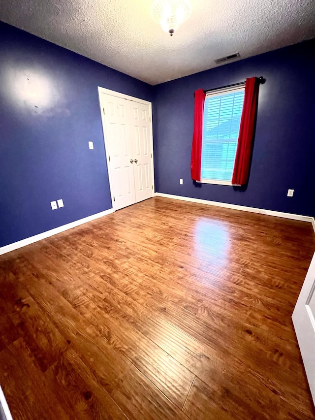 unfurnished bedroom featuring a closet, hardwood / wood-style floors, and a textured ceiling