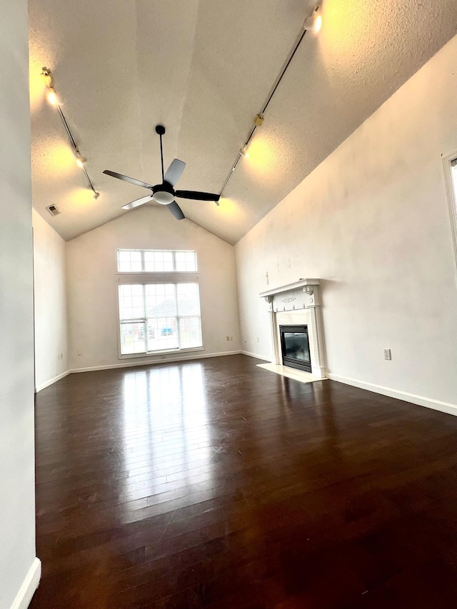 unfurnished living room featuring lofted ceiling, rail lighting, dark hardwood / wood-style floors, and ceiling fan